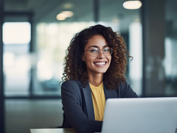 Jeune femme souriant dans un bureau devant un laptop